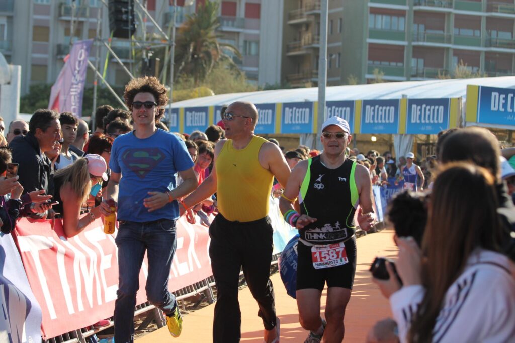 in mezzo a due ali di folla Bernardo mentre accompagna correndo l'arrivo del suo compagno di staffetta all'ironman di Pescara in cui Bernardini ha svolto la frazione di nuoto