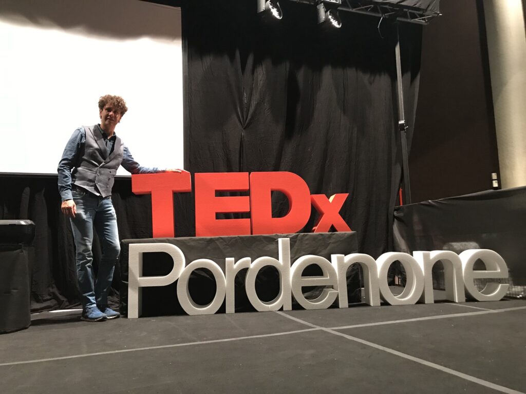 Bernardo posa di fianco alla scritta TedX Pordenone dopo aver fatto lo speech