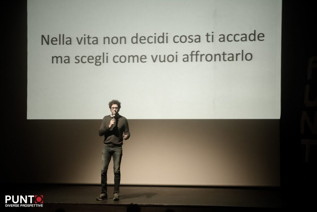 Bernardo sul palco dell'evento Punto diverse prospettive mentre parla di come nella vita non si possa decidere cosa ci accada ma possiamo scegliere come affrontarlo